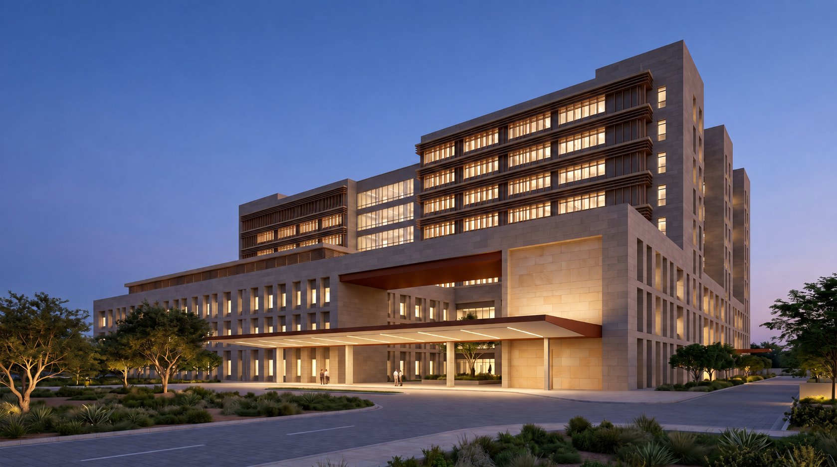 Exterior of a multi-storey cancer hospital at dusk, with a deep entrance canopy and stone-clad ward blocks above.