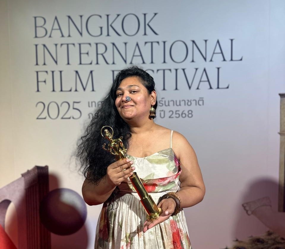 Nidhi Saxena on stage holding an award at the Bangkok International Film Festival, 2025.